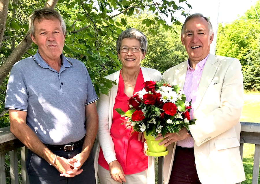 Mary Gillis being celebrated for 45 years of service with bouquet of flowers by coworkers